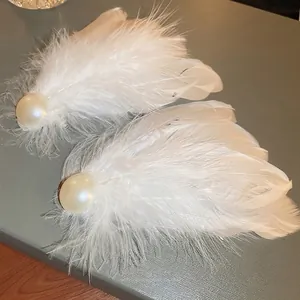 Elegant white feather hair clips with large faux pearls on a textured display box
