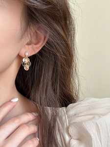 Détail de boucles d'oreilles grappes en résine dorée avec pendentifs champagne