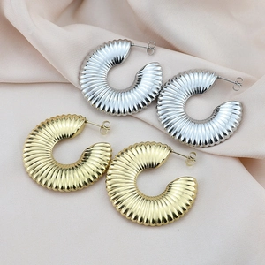 Textured hollow C-shaped gold and silver earrings on elegant pink silk background