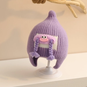 Detail of purple knitted baby hat featuring cute cartoon doll with braids and ear protection