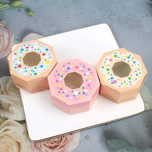 Detail of three hexagonal donut-themed favor boxes with clear windows on white tray