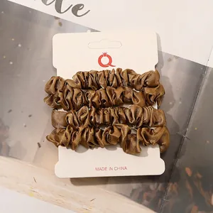 Detail of 4-piece bronze satin scrunchies set with silky texture on display card
