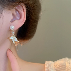 Détail de boucles d'oreilles pétales avec perles et cristaux portées à l'oreille