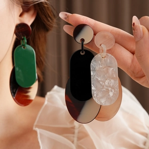 Detail view of acrylic geometric earrings in green, brown, black, and white color options