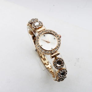 Detailed view of luxury golden quartz watch with sparkling rhinestones and floral bracelet