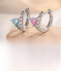 Detail of silver hoop earrings featuring pink and blue heart-shaped cubic zirconia crystals
