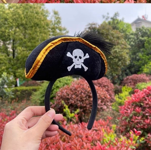 Close-up of pirate headband with gold-trimmed hat, skull motif, and black feathers decoration