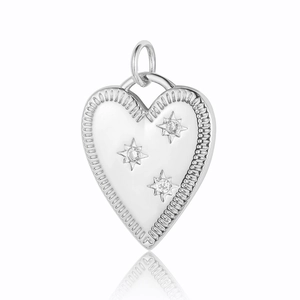 Macro shot of silver heart pendant with beaded edges and star zircon stone inlay