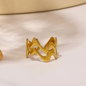 Polished gold double-layer wave ring made of stainless steel on a warm white background
