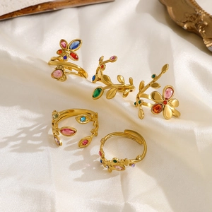 Artistic layout of gold leaf rings with rainbow zircon stones on white silk background
