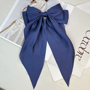 Detail of elegant navy blue satin hair clip with large bow and long streamers