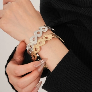 Detail of gold and silver hollowed-out metal cuff bracelets on a model's wrist
