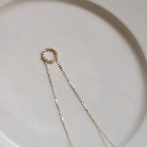 Detail of s925 silver 14k gold necklace with zircon paved circle pendant on white ceramic