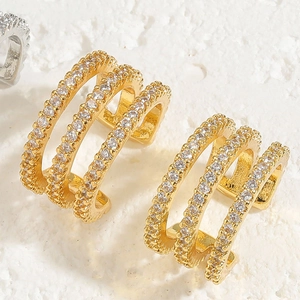 Detail shot of 18K gold plated X-shaped ear cuffs with three rows of sparkling zircon stones