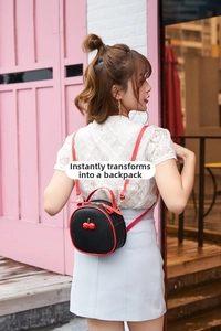 Detail of lychee textured leather mini backpack with cherry accents and red straps