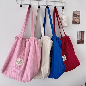 Striped drawstring tote bags in pink, white, blue and red colors hanging on a wall