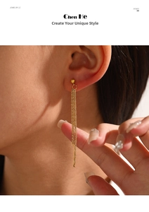 Close-up of golden long tassel drop earrings with fine chains worn by a model