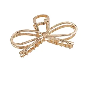 Elegant champagne gold metal bow hair claw clip with a glossy finish for women