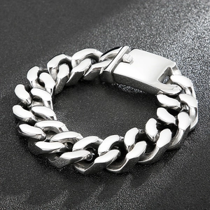 Detailed top view of a heavy silver-colored stainless steel Cuban chain on textured stone