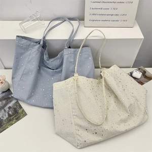Detail view of canvas tote bags with silver star patterns in blue and white colors