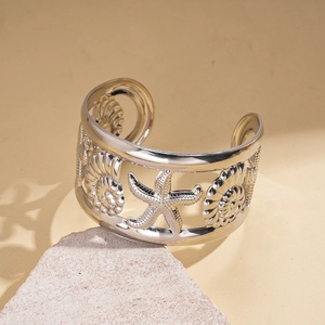Detailed view of silver open cuff bracelet with intricate starfish and seashell carvings