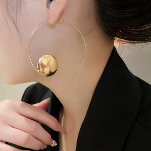 Close-up of gold geometric hoop earrings with hammered metal discs on female model