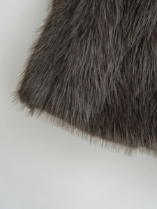 Macro view showing the fluffy long-pile texture of the dark brown faux fur vest material
