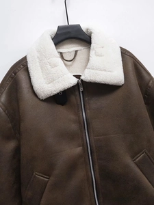 Detail of dark brown leather jacket with white faux fur collar and metal zipper
