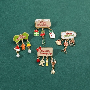 Christmas enamel brooches with dangling bells and snowmen on a textured green background