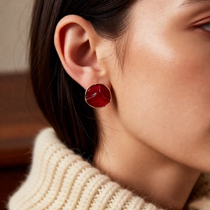 Close-up of model wearing a vintage red enamel round earring with gold-plated textured edges