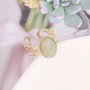 Detail of a vintage gold chain ring featuring a large oval pale green natural stone