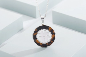 Dettaglio del ciondolo rotondo in tartaruga con quadrifoglio in argento su sfondo moderno