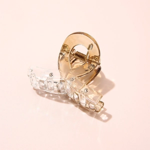 Macro shot of a transparent acetate mini hair claw clip with a durable metal spring