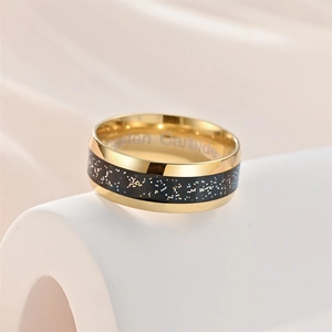 Golden tungsten carbide ring with star sky inlay displayed on a white stand