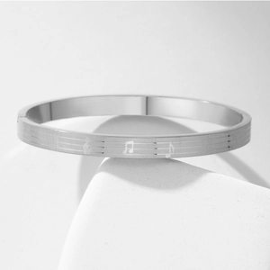 Macro shot of silver titanium steel bracelet with engraved music notes on white stone