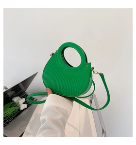 Detail of green pleated crescent bag with circular handle and detachable shoulder strap