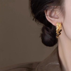 Vintage gold fluid metal earrings with brown beaded fringe tassels on female model