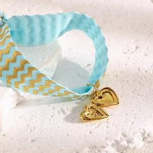 Detail of light blue wave pattern silk ribbon with gold heart pendants on stone