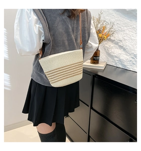 Detail of large capacity straw bucket bag with brown stripes and long crossbody strap