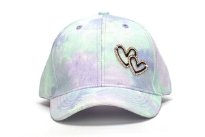 Detailed shot of tie-dye baseball cap featuring silver double heart rhinestone accents