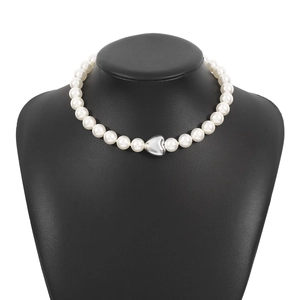 Elegant white pearl necklace with a silver heart pendant on a black bust mannequin