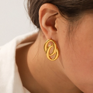 Minimalist gold-plated interlocking oval hoop earrings worn on a model with a white shirt