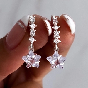 Macro shot of silver star drop earrings with sparkling cubic zirconia on simple ear hooks