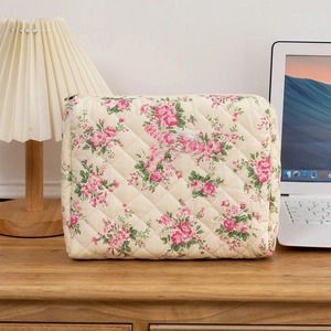 Close-up of quilted floral cotton makeup bag with a zipper on a warm wooden desk