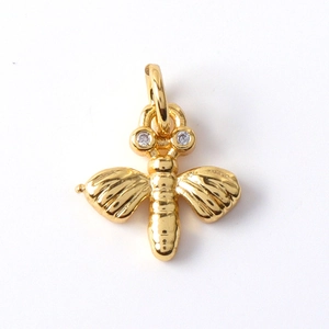 Detailed view of a gold-plated bee charm with sparkling cubic zirconia on white background