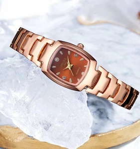 Close-up of rose gold tonneau quartz watch with crystals on marble background