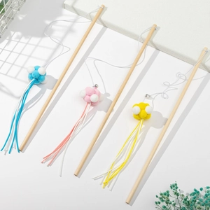 Three wooden cat wands with colorful plush balls, bells and tassels on a white surface
