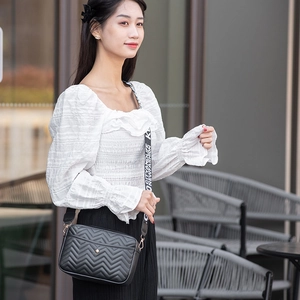 Detail of black chevron quilted crossbody bag with stylish lettered wide strap