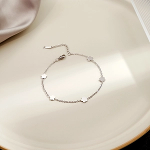 Macro detail of silver five-petal flower charms on a minimalist delicate chain bracelet