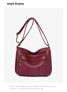Detail view of burgundy crossbody bag featuring soft lychee texture and silver zippers